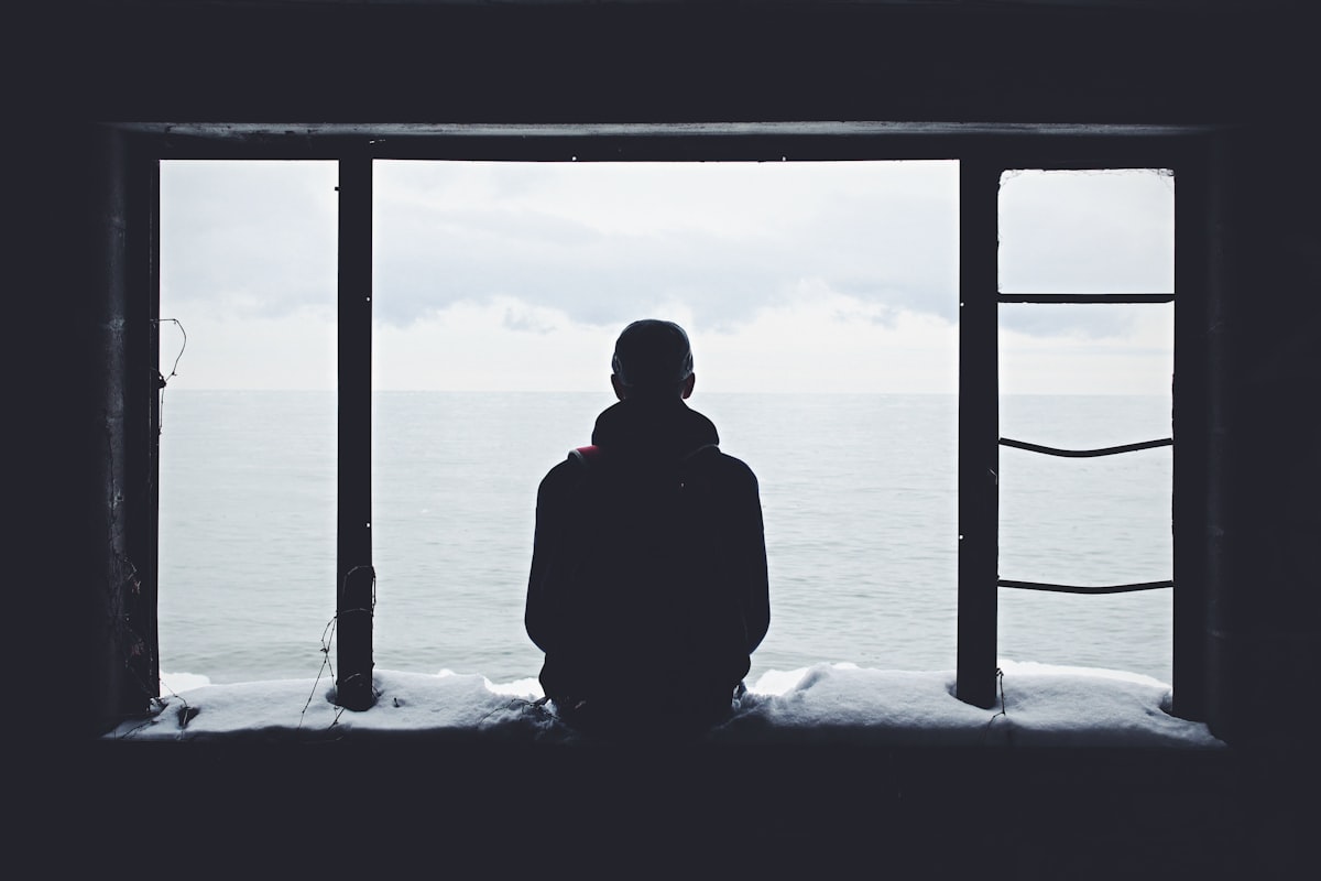 Person sitting alone looking out a window