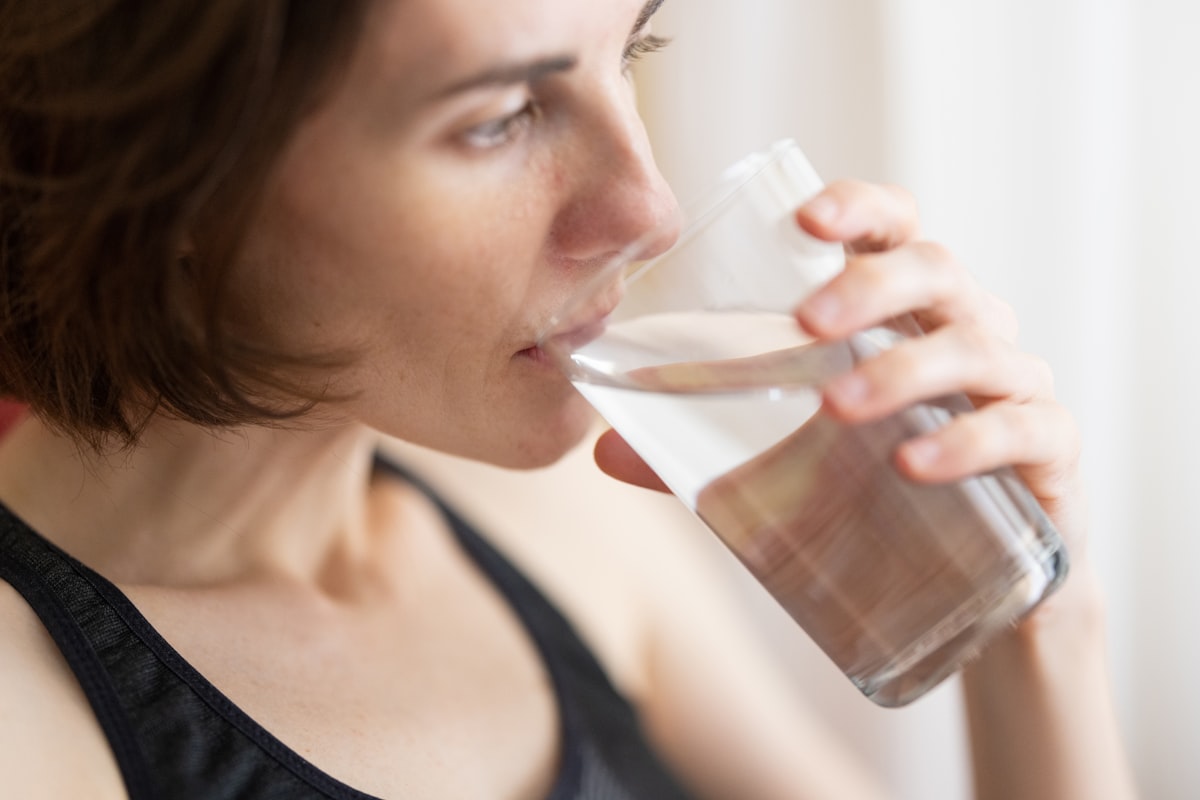 Person drinking a glass of water for hydration