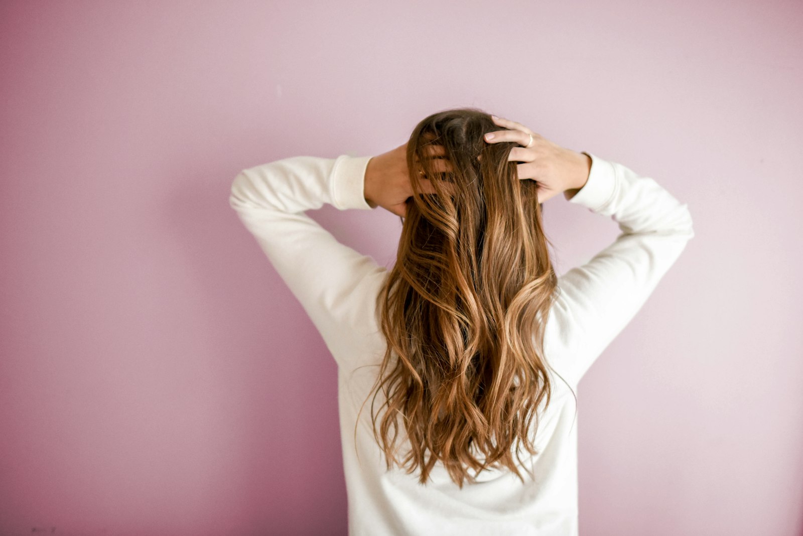 Woman with healthy shiny hair demonstrating at-home hair care between salon visits