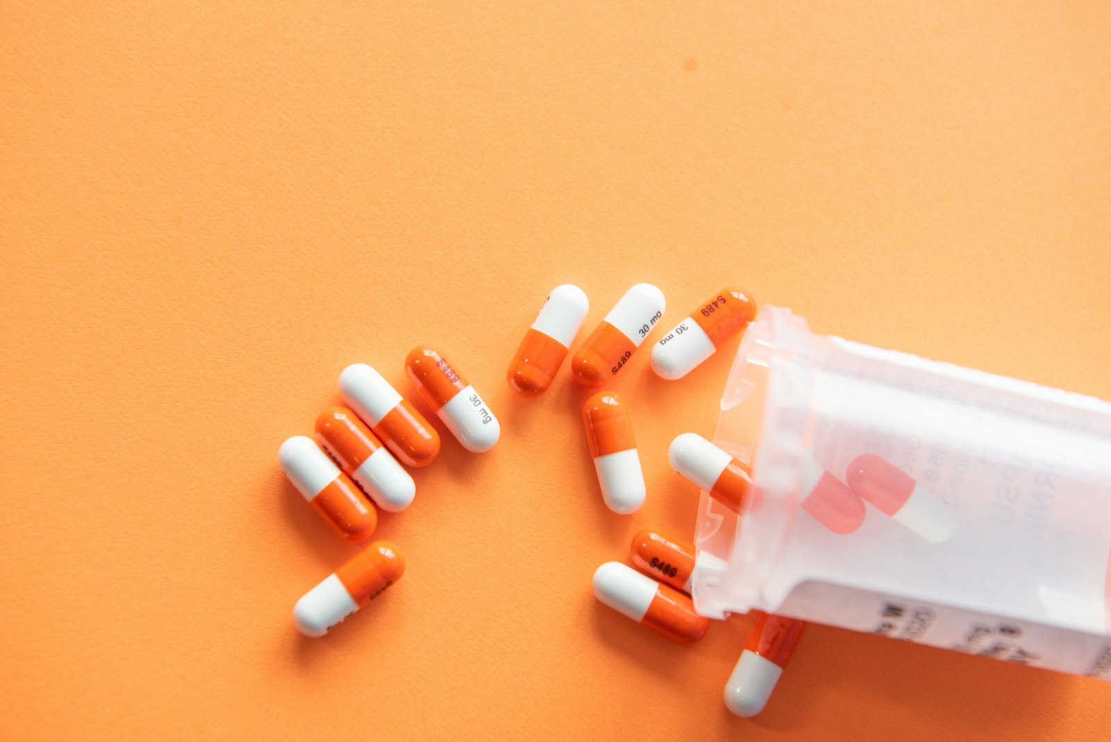 White and orange medication capsules representing a course of antibiotics